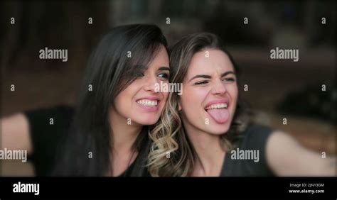 Girlfriends Taking Selfie Sticking Tongue Out Young Women Posing For Photo Holding Smartphone