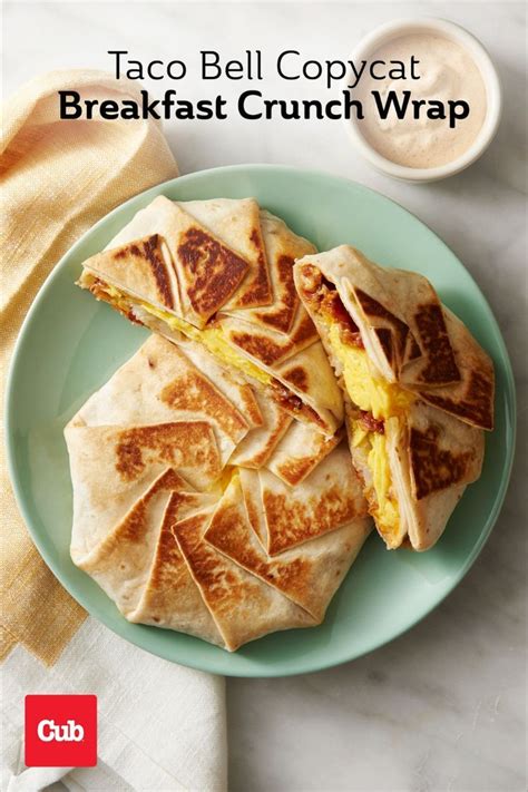 Two Breakfast Crunch Wraps Plated Next To A Ramekin Of Sauce Breakfast