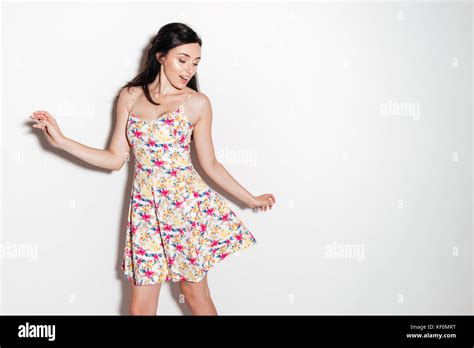 Cheerful Brunette Woman In Dress Dancing In Studio Over White