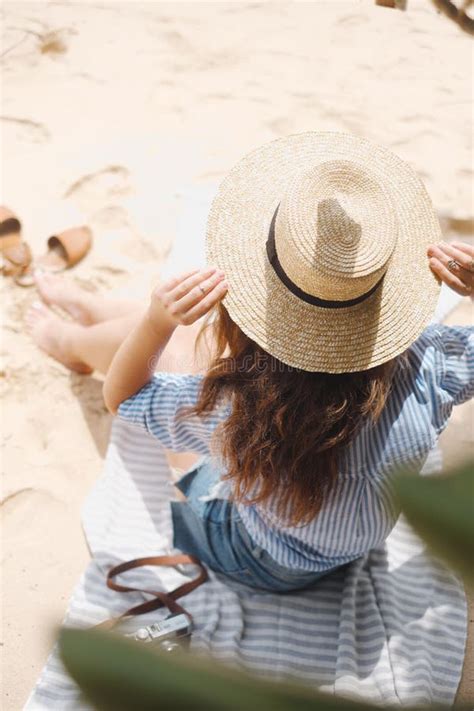 La Fille Du Dos Dans Le Chapeau S Assied Sur La Plage Photo Stock