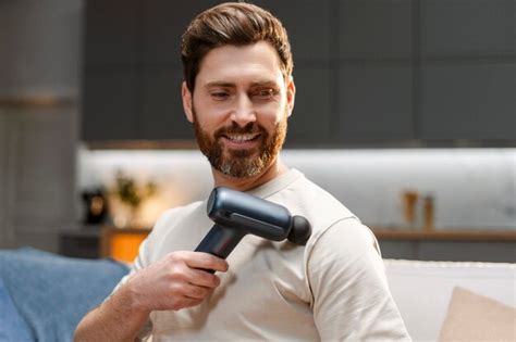 Premium Photo Portrait Of Middle Aged Bearded Man Using Massage Gun