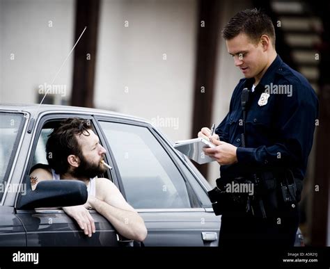 Traffic Cop Writing Ticket To Male Driver With Cigarette Stock Photo