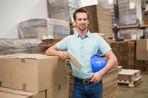 Premium Photo Smiling Warehouse Worker Leaning Against Boxes