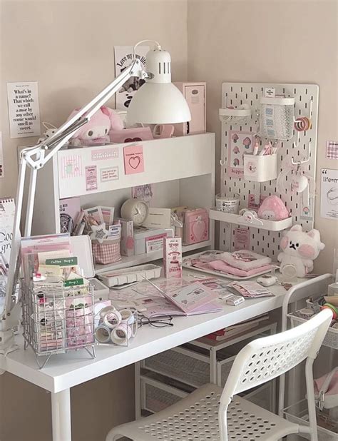 A White Desk Topped With Lots Of Clutter Next To A Wall Mounted Lamp