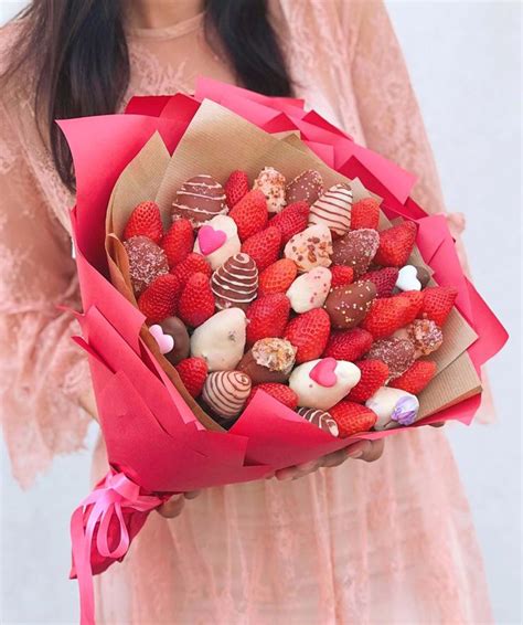 A Woman Holding A Bouquet Of Strawberries And Chocolates