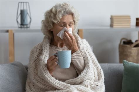 Sick Mature Woman With Blanket Sneezing Coughing Blowing Nose In