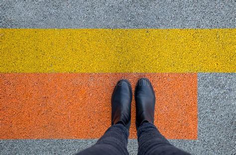 Black Shoes Standing On The Asphalt Concrete Floor With Yellow And