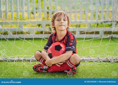 Little Cute Kid Boy In Red Football Uniform Playing Soccer Football On