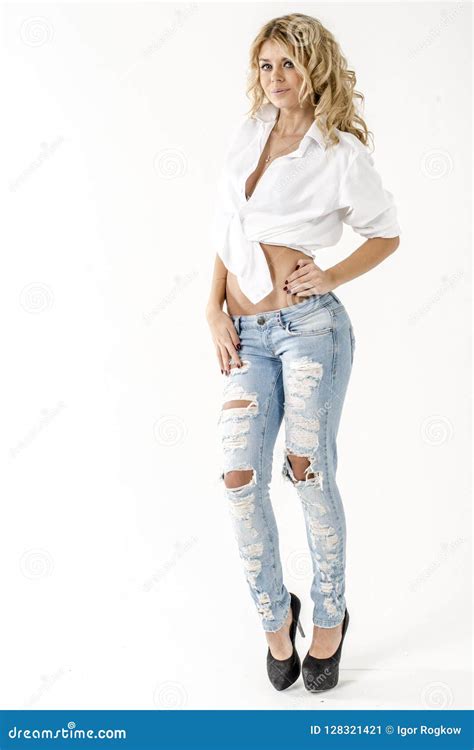 Blonde Hermoso Joven De La Muchacha En Una Camisa Blanca Y Vaqueros Con Huecos Imagen De Archivo