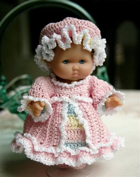 A Small Doll Wearing A Pink Dress And Bonnet