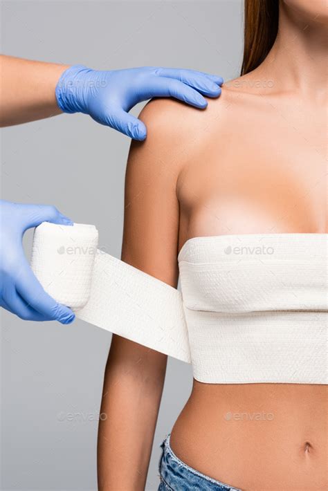 Cropped View Of Doctor Wrapping Breast Of Naked Woman With Elastic Bandage Isolated On Grey