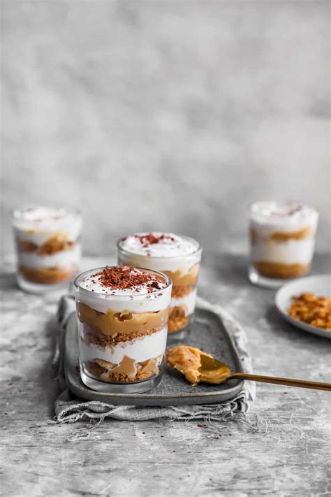 Three Desserts Are Sitting On A Tray With Spoons