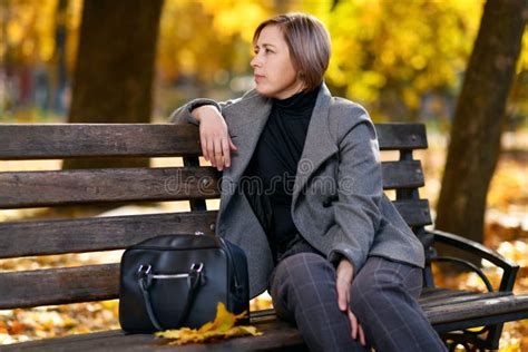 Beautiful Woman Portrait She Is Sitting On A Bench In The Autumn Park