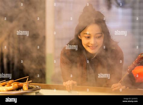 Young Chinese College Student Holding Tanghulu Selecting Food At Market