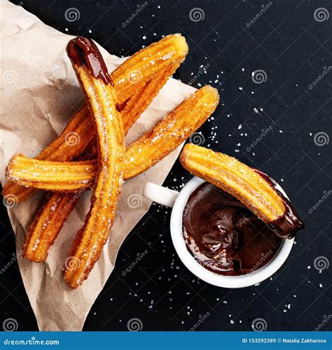 Churros With Sugar Dipped In Chocolate Sauce On A Black Background