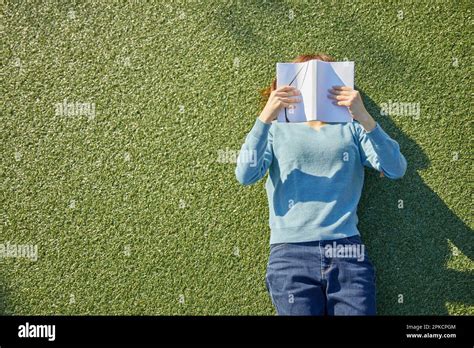 Woman Reading A Book Lying Down On The Artificial Grass Stock Photo Alamy