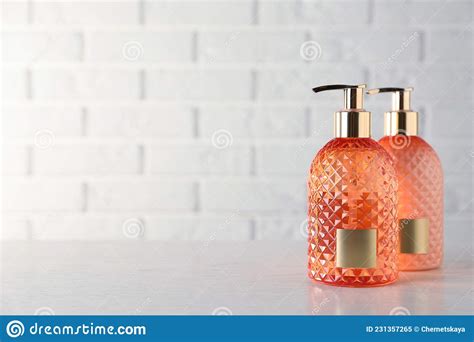 Stylish Dispensers With Liquid Soap On Wooden Table Near White Brick