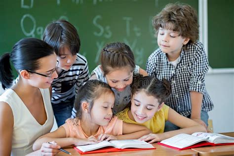 Niños De La Escuela Primaria Que Se Sientan En Piso De La Sala De Clase