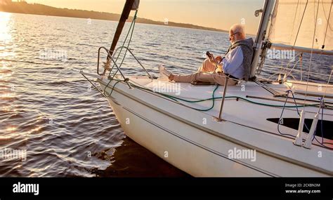 Reading On Board Side View Of A Relaxed Senior Man Sitting On The Side