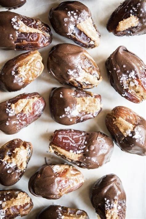 Chocolate Covered Almonds Are Arranged On A White Surface