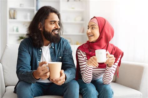 Man And Woman Sitting On A Couch Holding Coffee Cups Stock Image