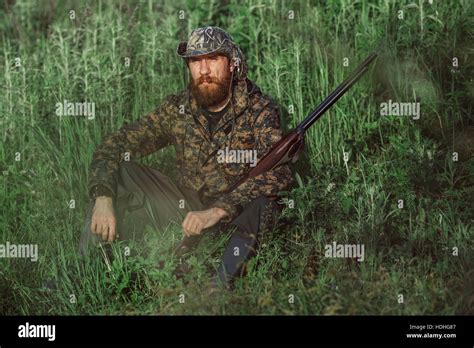 Hunter Holding Rifle While Sitting On Grassy Field Stock Photo Alamy