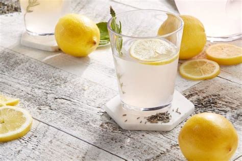 A Glass Filled With Water Next To Lemons