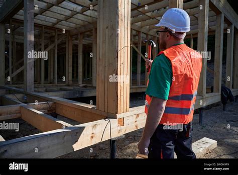 Carpenter Constructing Two Story Wooden Frame House Near The Forest