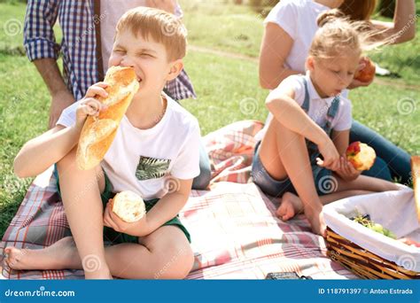 Uma Imagem Das Crian As Que Sentam Se Na Grama E Que Comem O Alimento A