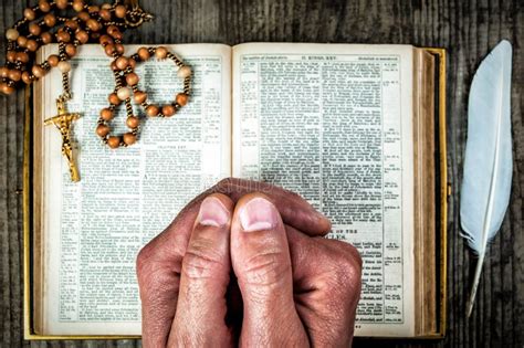 Las Manos Rezando Por La Sagrada Biblia Y El Rosario Foto De Archivo