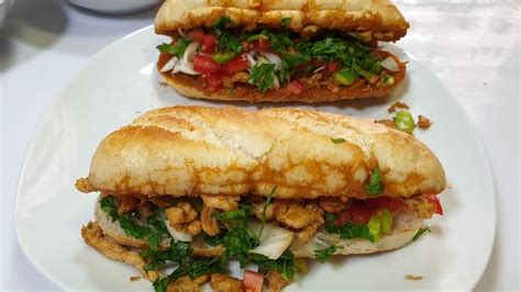 Two Sandwiches Are Sitting On A Plate With Meat And Veggies In Between Them