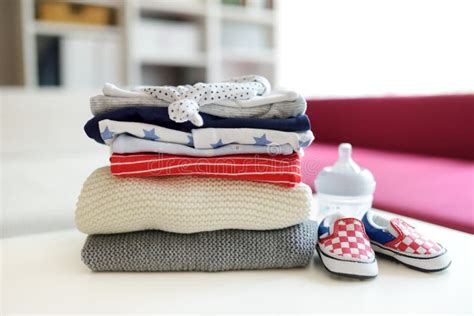 A Pile Of Baby Clothes Feeding Bottle And Little Newborn Shoes