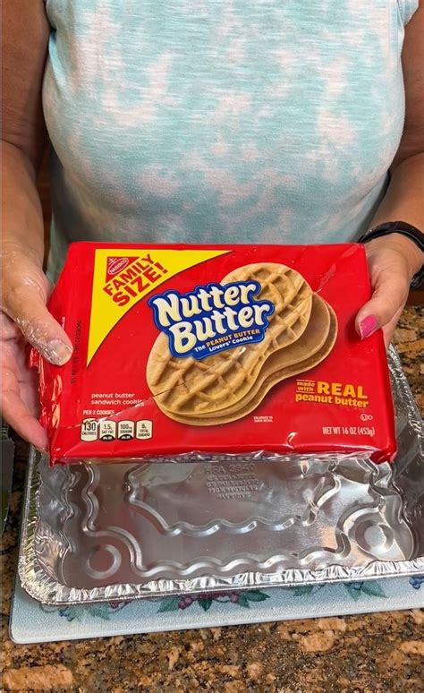 A Woman Holding A Box Of Nutter Butter Crackers On Top Of A Cookie Sheet