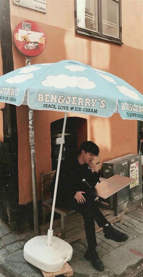 A Man Sitting On A Bench Under An Umbrella