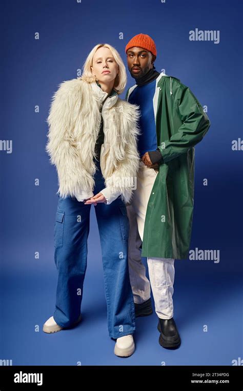 Stylish Interracial Models In Winter Attire On Blue Backdrop Blonde Woman And African American