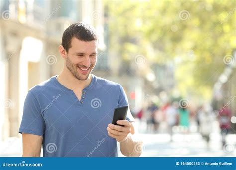 Homem Feliz Caminhando Usando Telefone Celular Na Rua Imagem De Stock