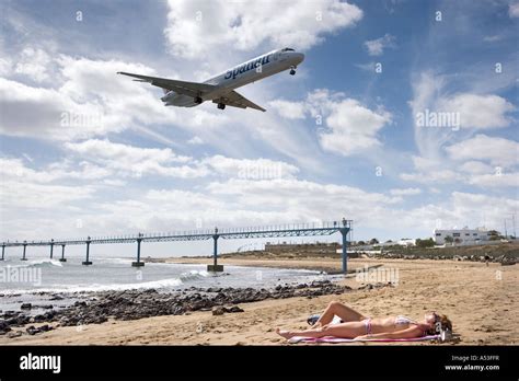 Plane Lands Over Sunbather At Arrecife Airport Lanzarote Canary Stock