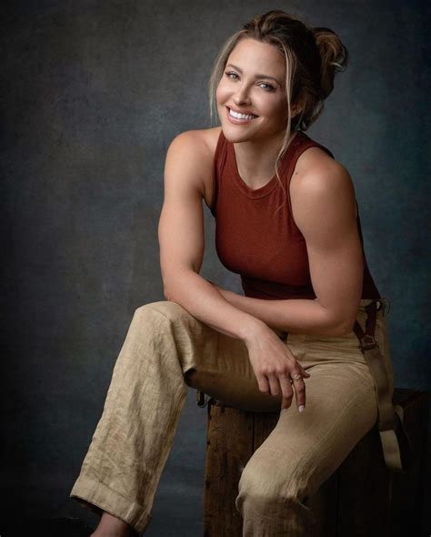 A Woman Sitting On Top Of A Wooden Stool Smiling At The Camera While