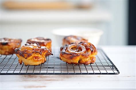 Freshly Baked Cinnamon Rolls On A Wire Cooling Rack With Icing