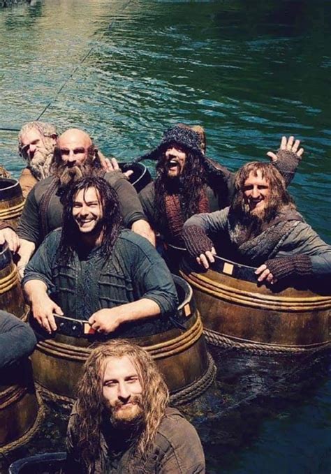 A Group Of Men Riding On Top Of Wooden Boats In The Water With Long Hair