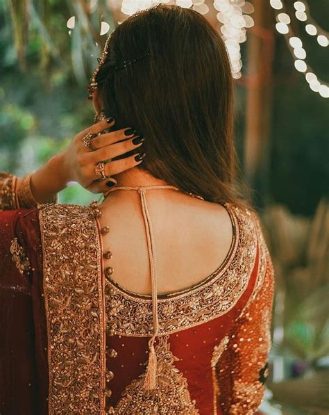 The Back Of A Woman S Head Wearing A Red And Gold Lehenga