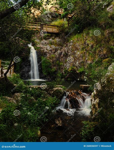 Vertical Scenic View Of Waterfall Flowing Through Cliffs With Lush