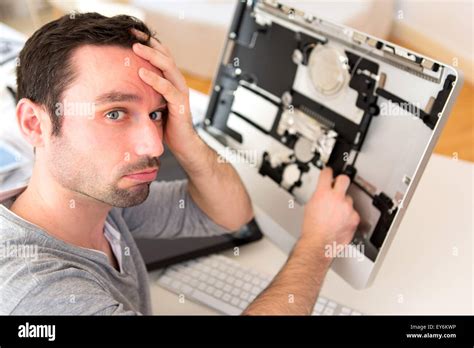 View Of A Young Attractive Man Trying To Repair Computer Stock Photo