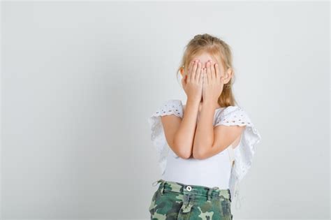 Petite Fille En T Shirt Blanc Jupe Couvrant Les Yeux Avec Les Mains