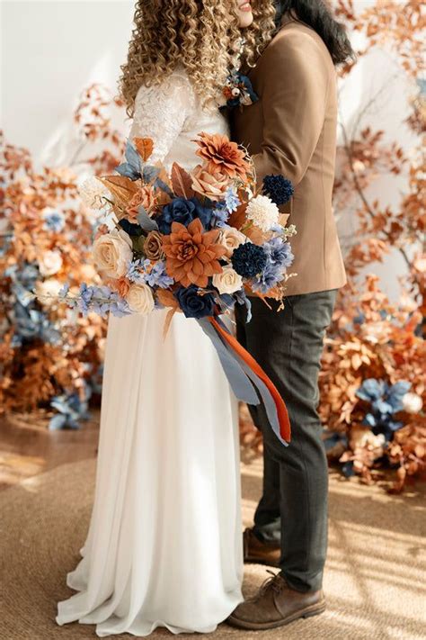 A Man And Woman Standing Next To Each Other In Front Of A Wall With Flowers