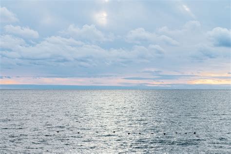 Mar en calma y cielo azul con cirros blancos el sol brilla a través de