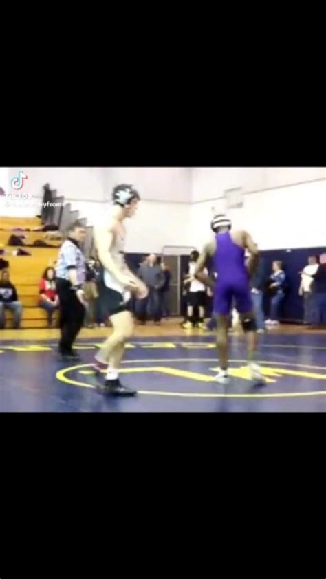 Two Men Wrestling In A Gym With People Watching