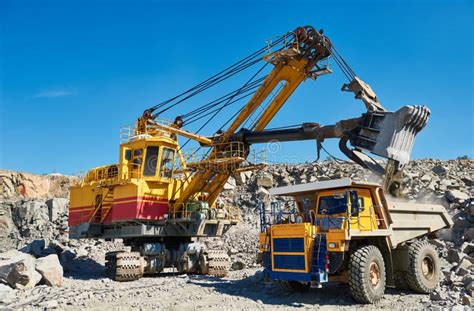 Excavator Loading Granite Or Ore Into Dump Truck At Opencast Stock