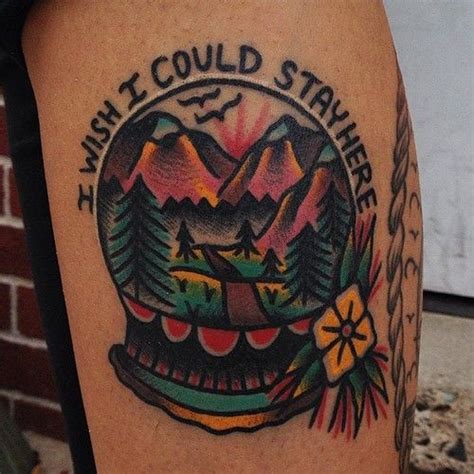 A Tattoo On The Leg Of A Person With Mountains In The Background And