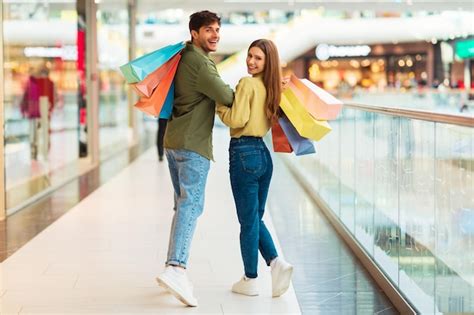 Pareja Alegre De Compras Caminando Mirando Hacia Atrás A La Cámara En